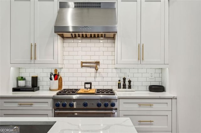 kitchen featuring decorative backsplash, high end stove, white cabinetry, and extractor fan