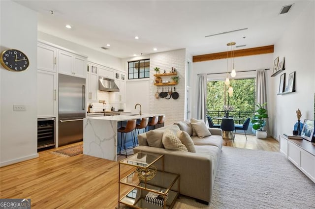 living area with recessed lighting, beverage cooler, visible vents, and light wood-type flooring