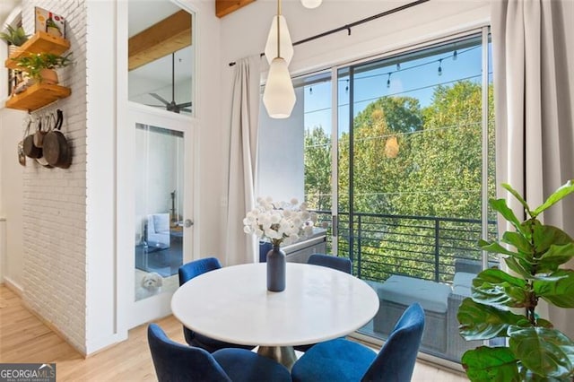 dining area featuring light wood-style flooring and brick wall