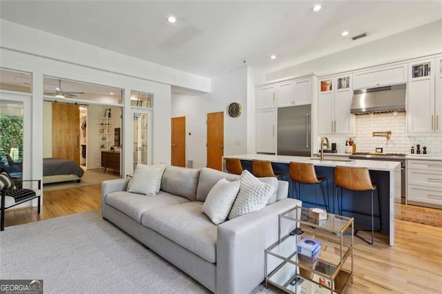 living area with recessed lighting, light wood-style flooring, a ceiling fan, and visible vents