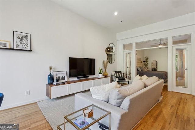 living area with baseboards, light wood-style floors, and a ceiling fan