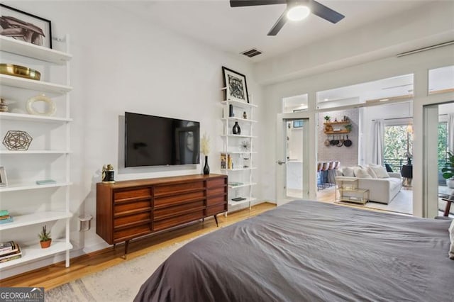 bedroom with visible vents, wood finished floors, access to exterior, and a ceiling fan