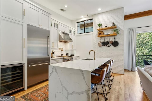 kitchen featuring visible vents, beverage cooler, under cabinet range hood, a sink, and appliances with stainless steel finishes