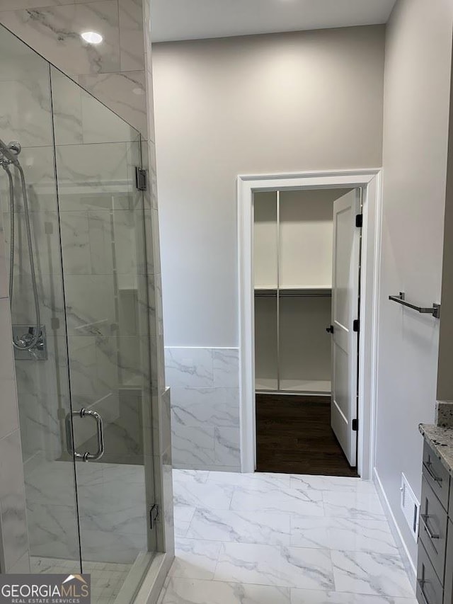 bathroom featuring vanity, visible vents, marble finish floor, and a marble finish shower