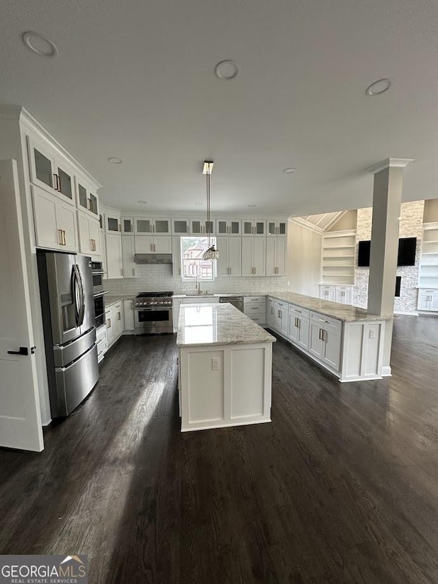 kitchen with a sink, stainless steel appliances, under cabinet range hood, and dark wood-style floors