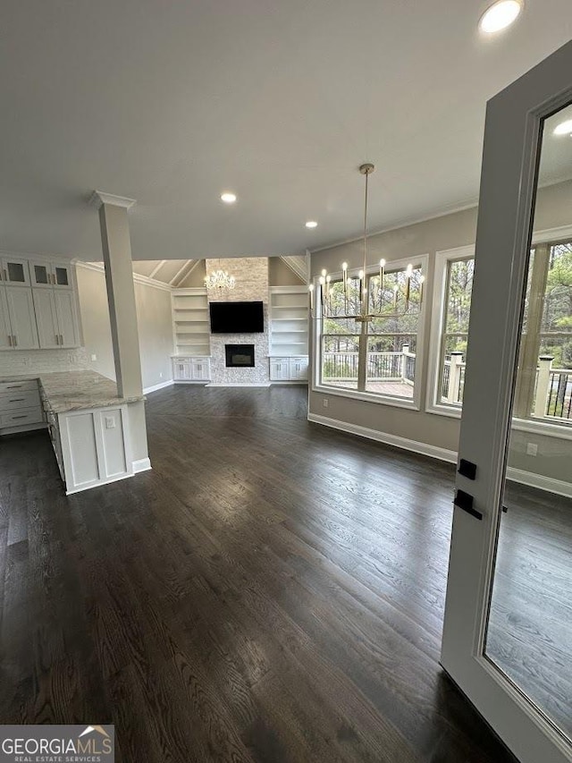 unfurnished living room featuring baseboards, dark wood finished floors, ornamental molding, recessed lighting, and a fireplace