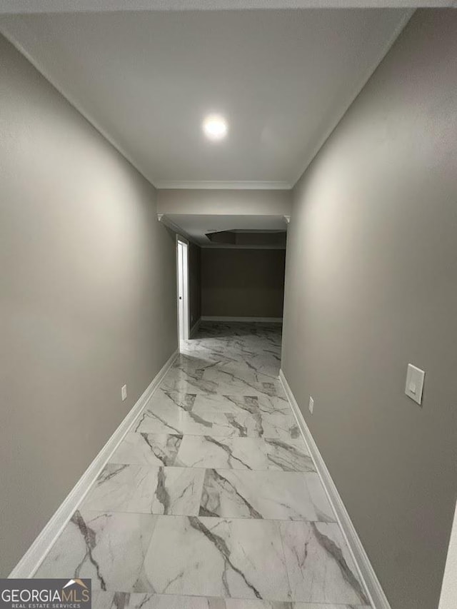 corridor featuring marble finish floor, crown molding, and baseboards