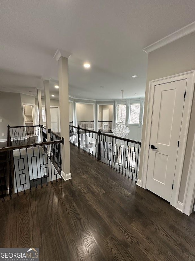 hall with an upstairs landing, baseboards, and wood finished floors