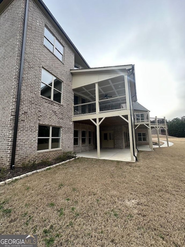 back of property with a yard, a patio, and brick siding