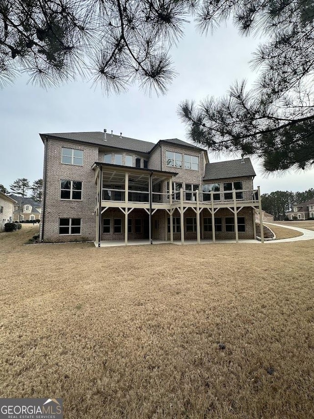 rear view of property with a yard and brick siding