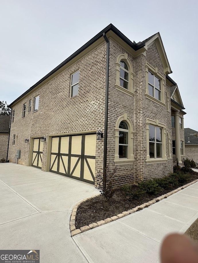 view of home's exterior featuring a garage, brick siding, and driveway