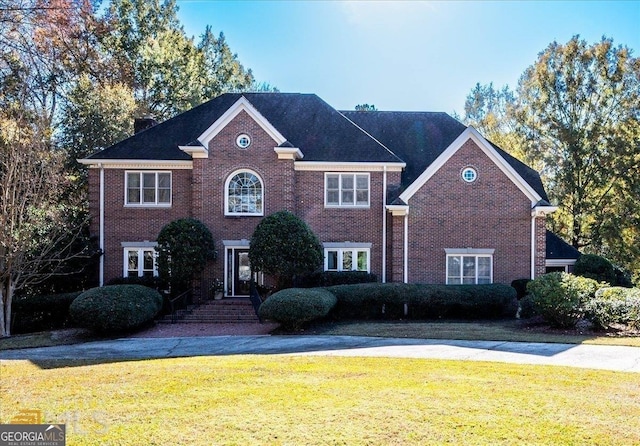 view of front facade with brick siding and a front lawn