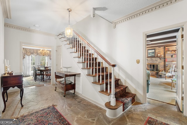 stairs with stone finish floor, a textured ceiling, crown molding, baseboards, and a chandelier