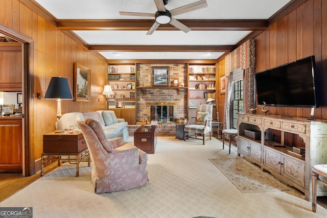 living area with beamed ceiling, wood walls, a fireplace, a textured ceiling, and a ceiling fan