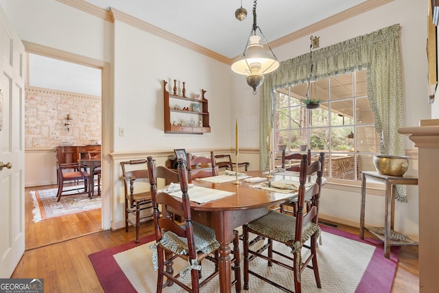 dining room featuring hardwood / wood-style flooring, visible vents, baseboards, and ornamental molding