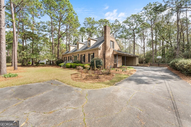 view of home's exterior featuring stone siding, a lawn, driveway, and a chimney