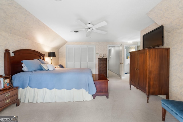 bedroom with a ceiling fan, a closet, wallpapered walls, lofted ceiling, and light colored carpet