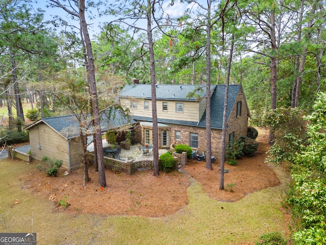 rear view of property featuring stone siding and a patio