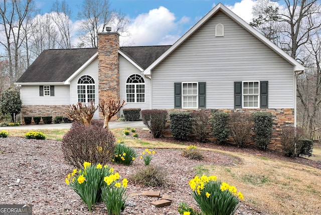 view of front of property with a chimney, stone siding, and a shingled roof