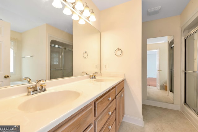 full bathroom with a sink, visible vents, a shower with door, and double vanity