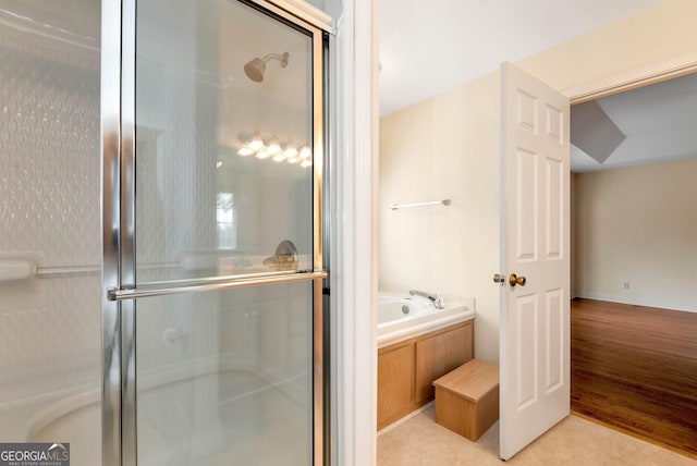 bathroom featuring a bath, a shower stall, and wood finished floors