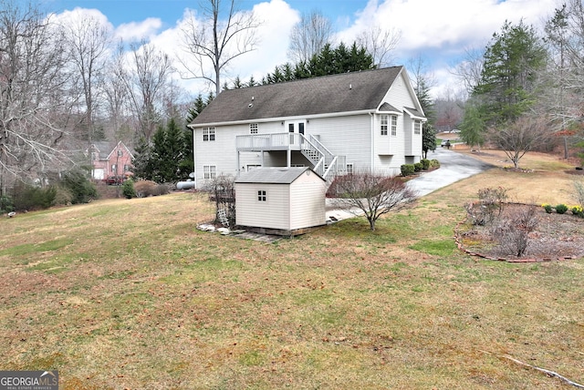 back of property featuring a lawn, a deck, a storage shed, an outdoor structure, and stairs