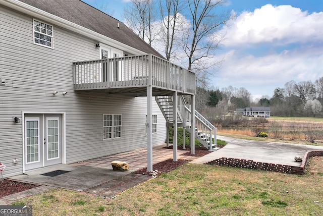 exterior space with stairway, a wooden deck, french doors, a patio area, and a lawn