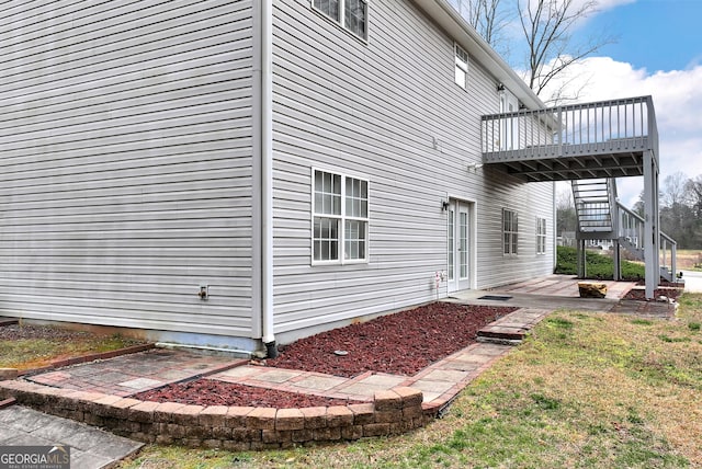 view of home's exterior featuring a wooden deck, a lawn, stairs, and a patio area