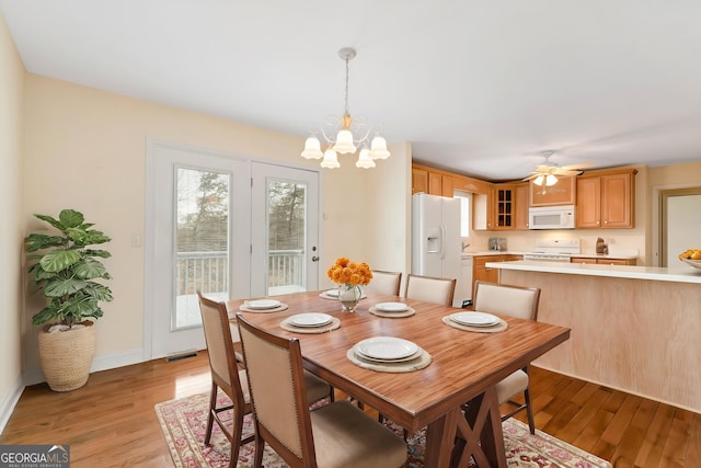 dining space with light wood finished floors, visible vents, ceiling fan with notable chandelier, and baseboards