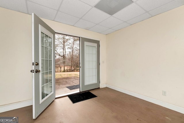 doorway with a drop ceiling, baseboards, concrete floors, and french doors