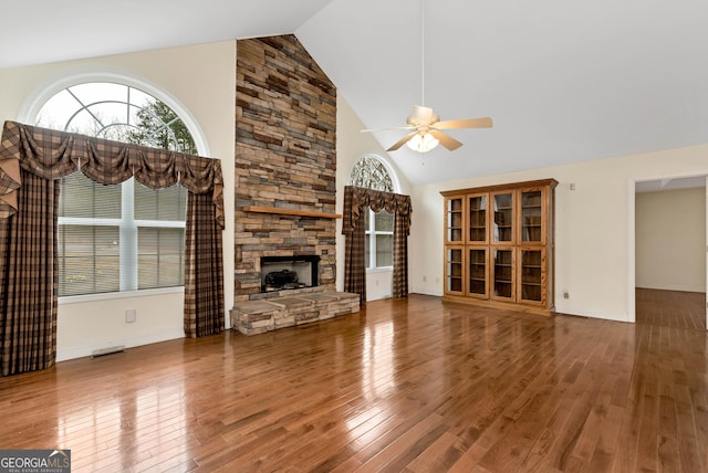 unfurnished living room with a stone fireplace, hardwood / wood-style flooring, a ceiling fan, and high vaulted ceiling