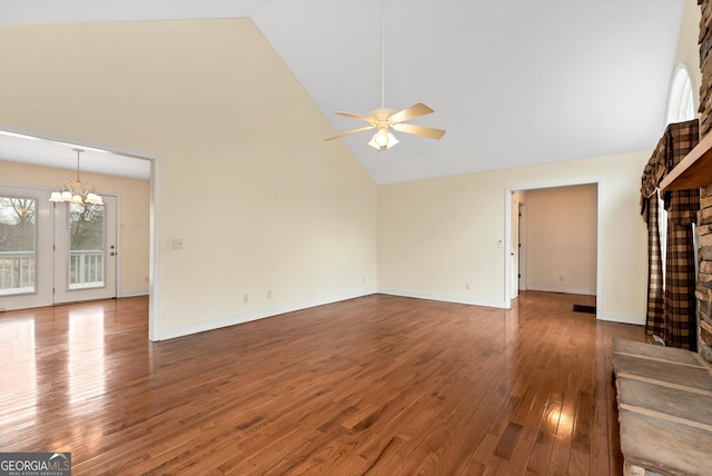 unfurnished living room featuring high vaulted ceiling, ceiling fan with notable chandelier, wood finished floors, a fireplace, and baseboards