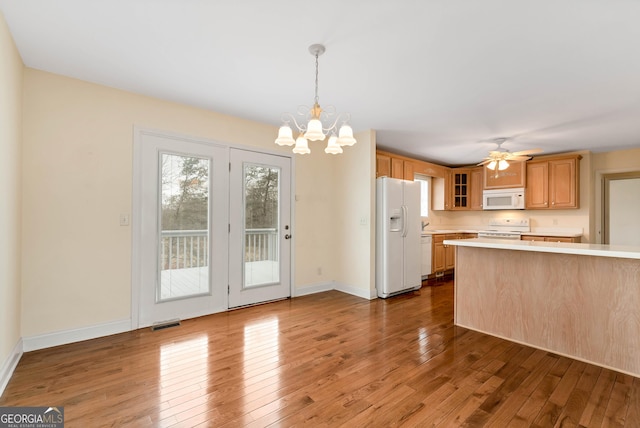 kitchen featuring hardwood / wood-style floors, white appliances, light countertops, glass insert cabinets, and baseboards