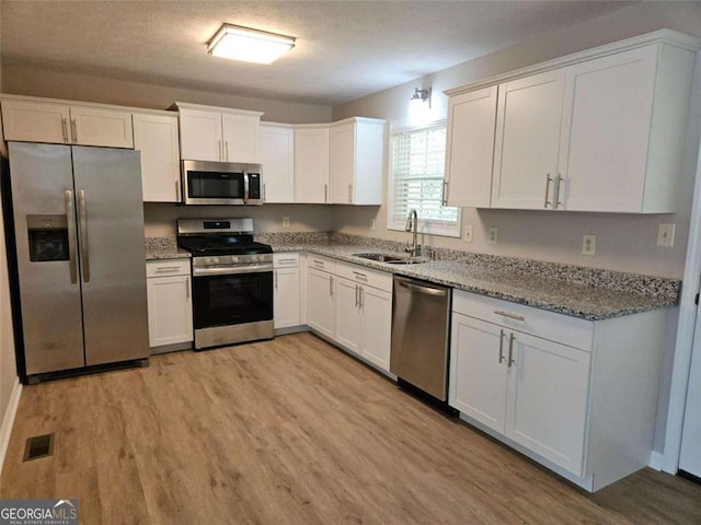 147 Mildred Ct, Dallas, GA 30157 - kitchen with appliances with stainless steel finishes, light wood-type flooring, white cabinets, and light stone counters