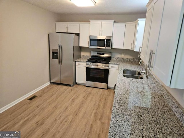 147 Mildred Ct, Dallas, GA 30157 - kitchen featuring stainless steel appliances, white cabinetry, light wood-style flooring, and light stone countertops