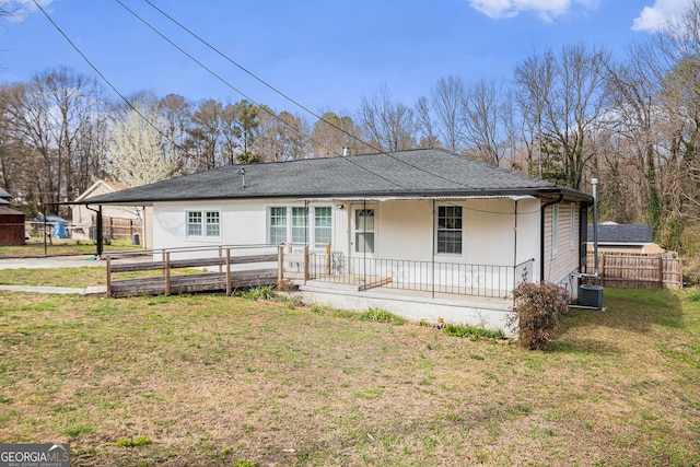 view of front of house with covered porch, a shingled roof, a front yard, and fence