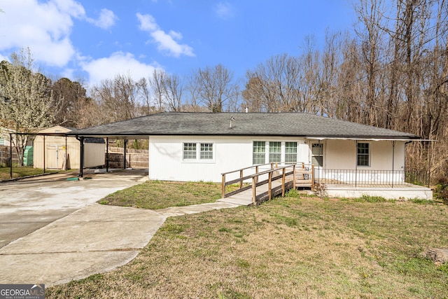 single story home with an attached carport, a front lawn, concrete driveway, covered porch, and a storage shed