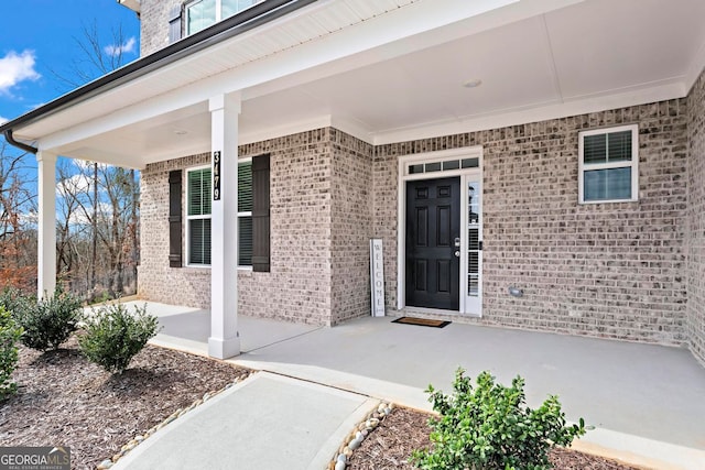 property entrance with a patio area and brick siding