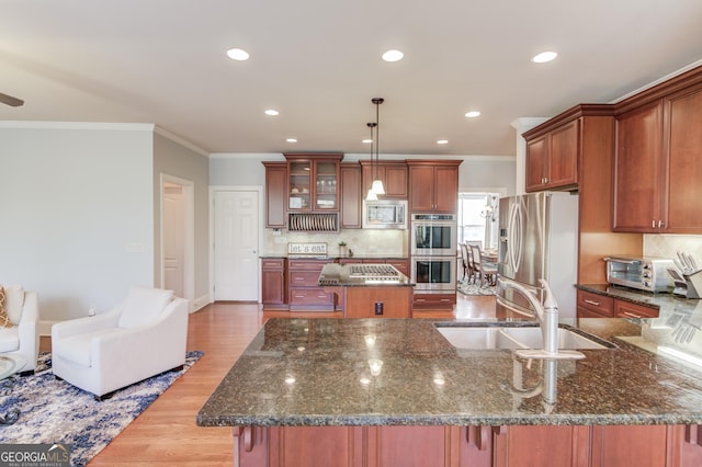 kitchen with a kitchen island, dark stone counters, light wood-style flooring, a sink, and stainless steel appliances