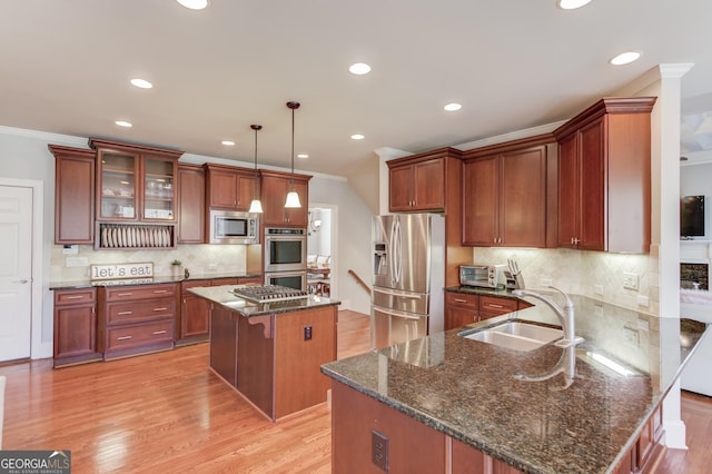 kitchen with a kitchen bar, ornamental molding, appliances with stainless steel finishes, a peninsula, and a sink