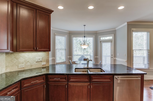 kitchen featuring wood finished floors, dark stone counters, a sink, decorative backsplash, and crown molding