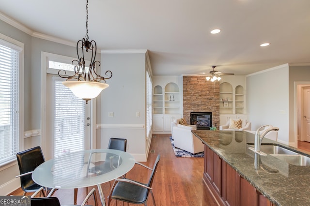 dining room featuring ornamental molding, a fireplace, and wood finished floors