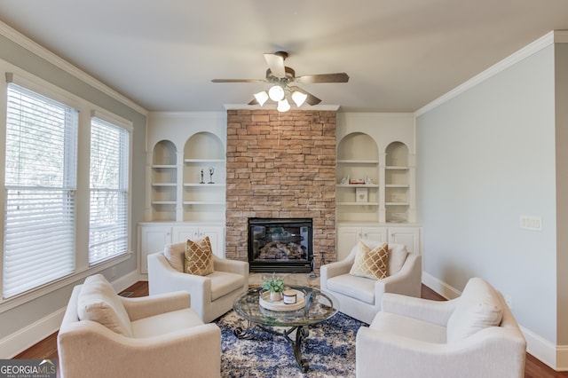 living area with built in features, baseboards, crown molding, and a ceiling fan