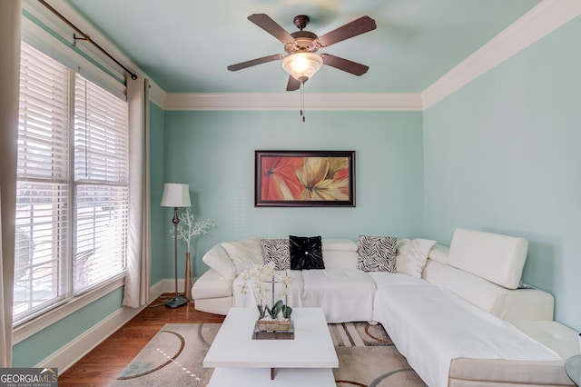 living area featuring baseboards, a ceiling fan, wood finished floors, and crown molding