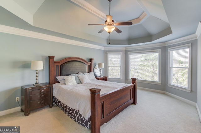 bedroom with a tray ceiling, multiple windows, light carpet, and ornamental molding