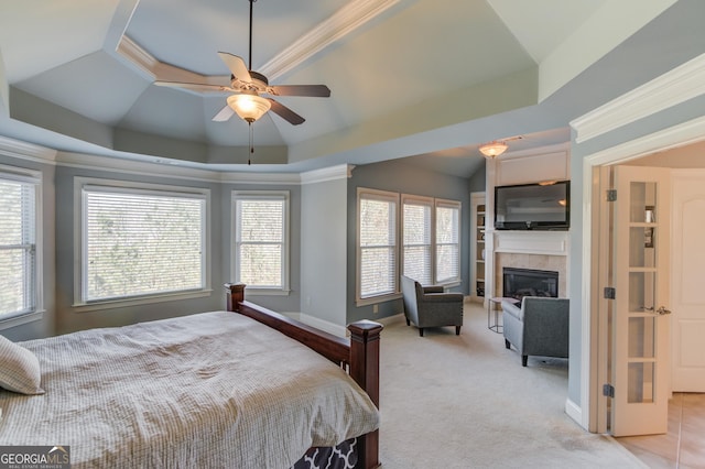 bedroom with crown molding, baseboards, a tiled fireplace, light carpet, and a raised ceiling