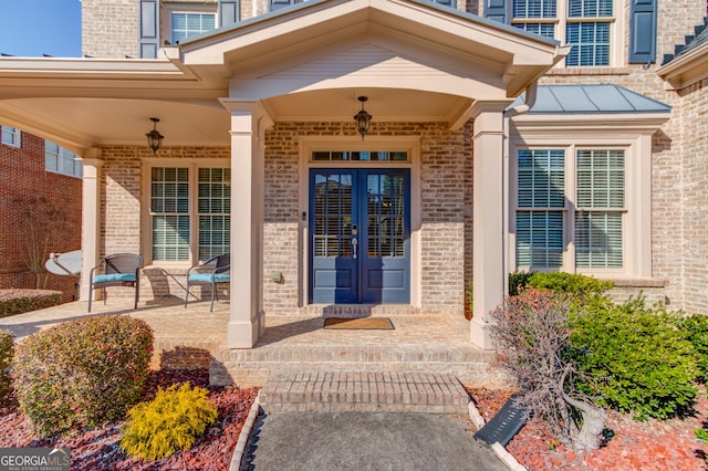 entrance to property with brick siding, french doors, and a standing seam roof