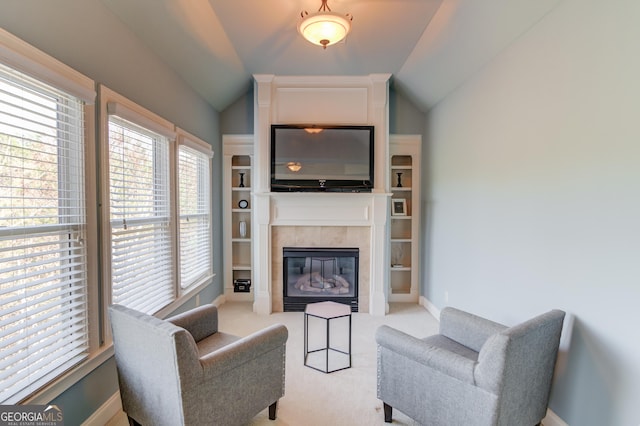 living area featuring lofted ceiling, light colored carpet, baseboards, and a tile fireplace