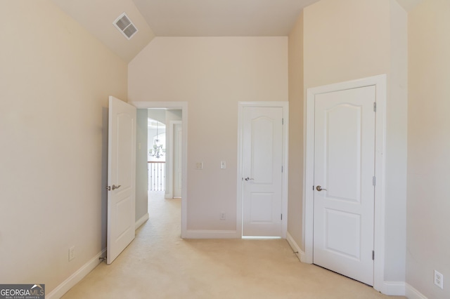 unfurnished bedroom featuring vaulted ceiling, baseboards, visible vents, and light carpet