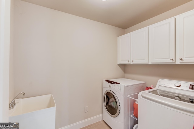 laundry room with baseboards, washing machine and dryer, light tile patterned floors, cabinet space, and a sink